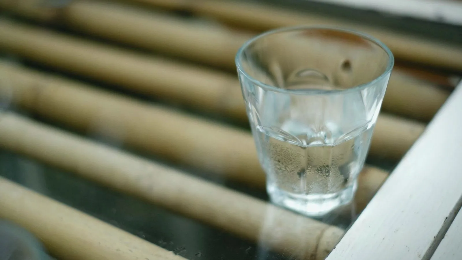 A small glass of clear liquid on a bamboo mat.
