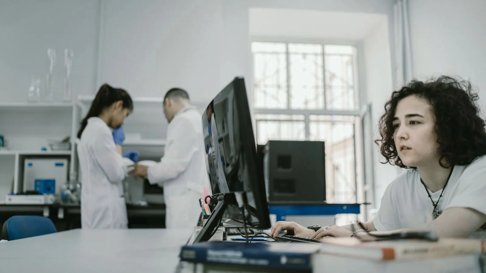 A researcher working at a monitor in a laboratory with colleagues behind