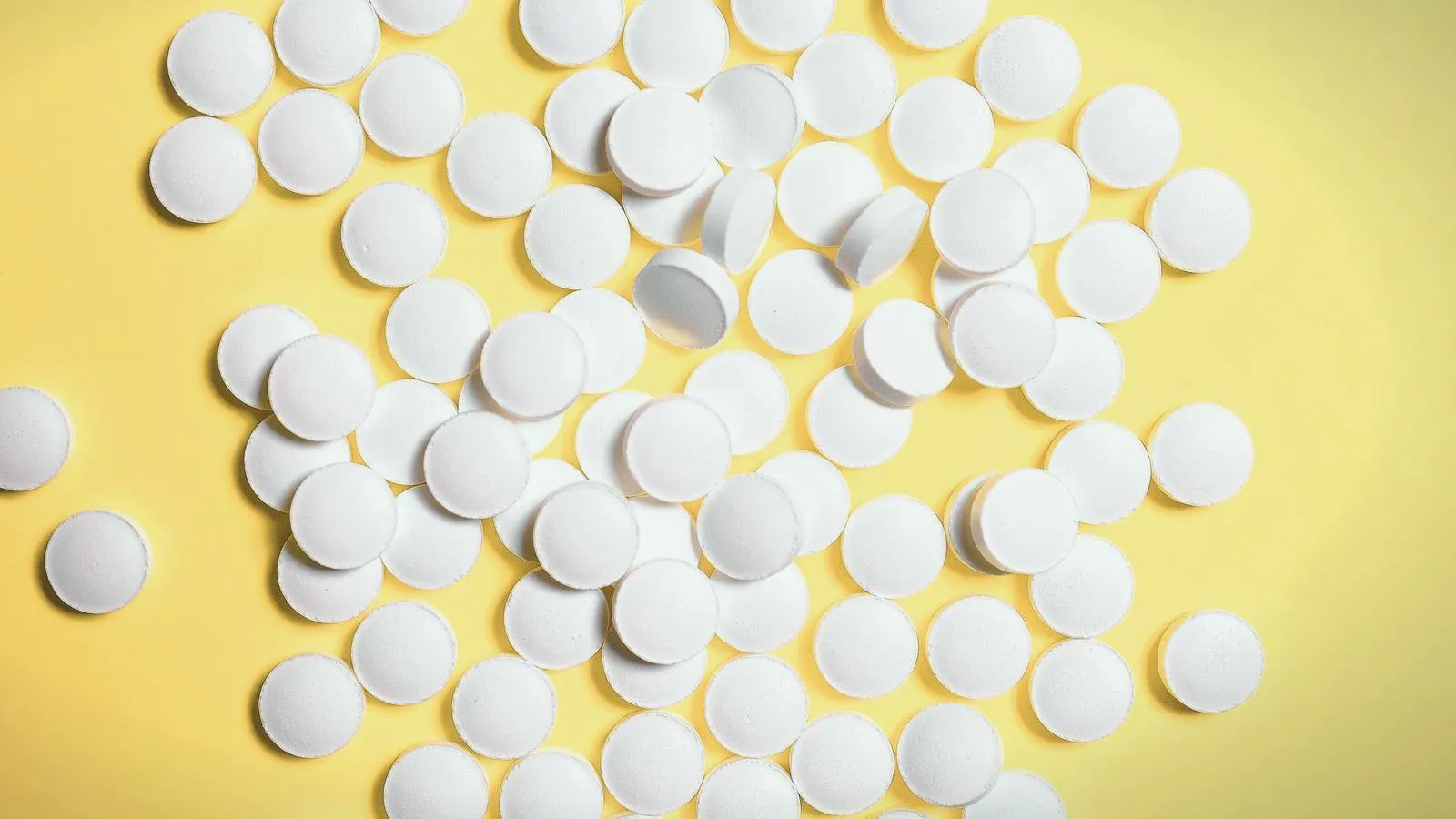 Plain white tablets scattered across a yellow surface