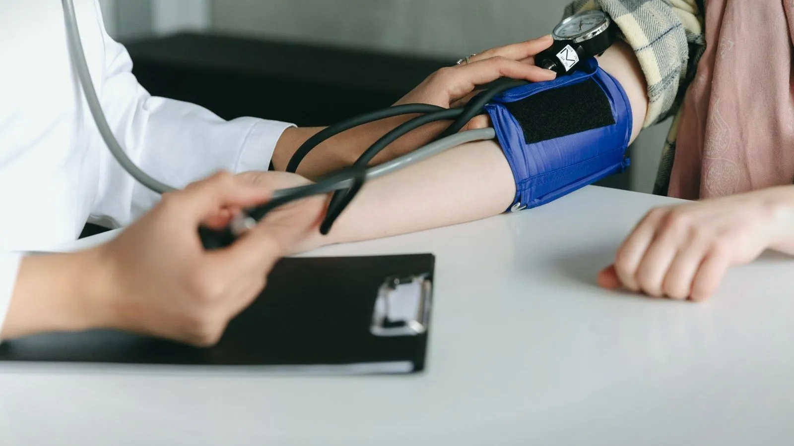 A clinician taking a blood pressure reading from a cuff on a patient's upper arm