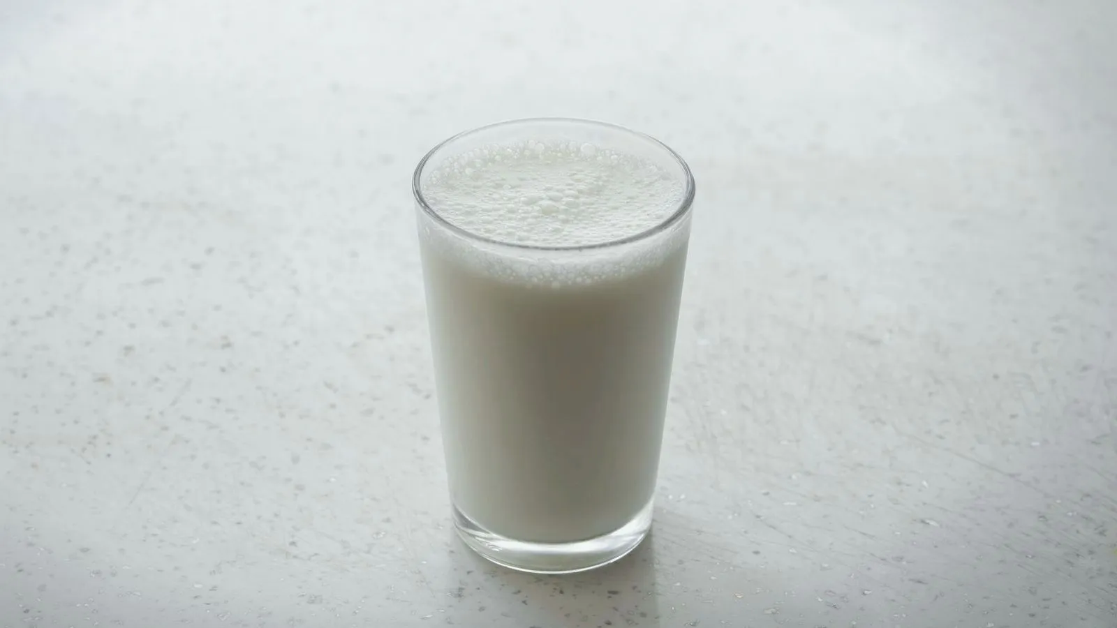 A glass of milk on a pale speckled surface