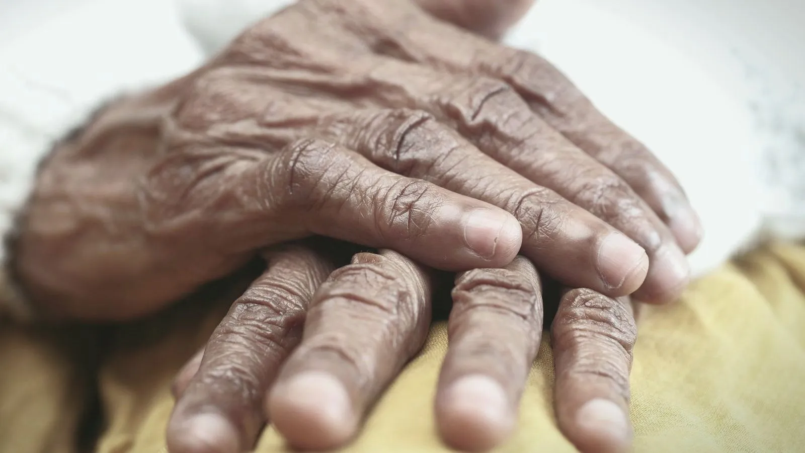 Two older hands resting one on top of the other