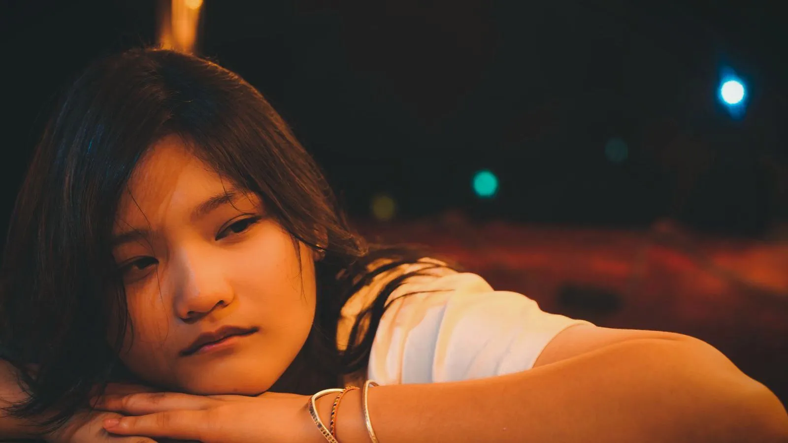 A teenage girl resting her head on her arms in dim light