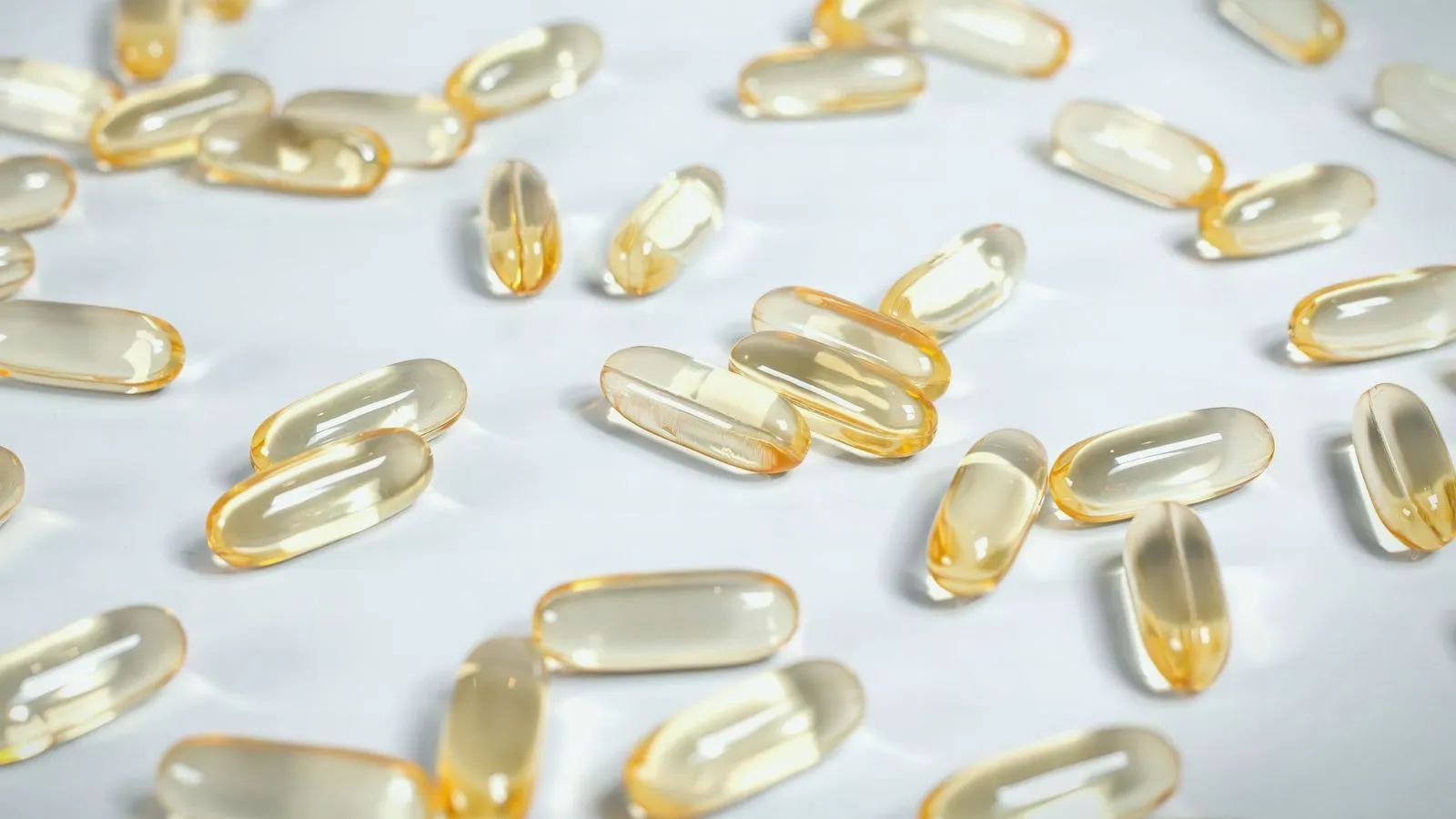 Golden softgel capsules scattered across a white surface