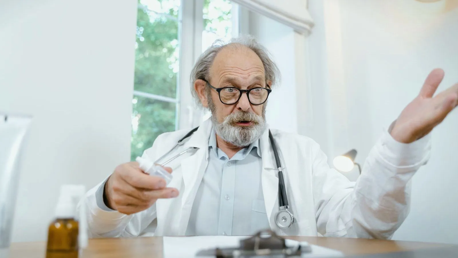 A doctor at a desk gestures while explaining, seen from the patient's side of the desk