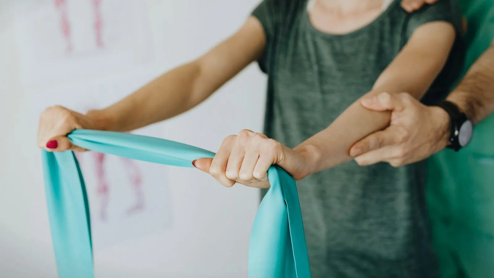 A therapist guiding a person stretching a resistance band between both hands