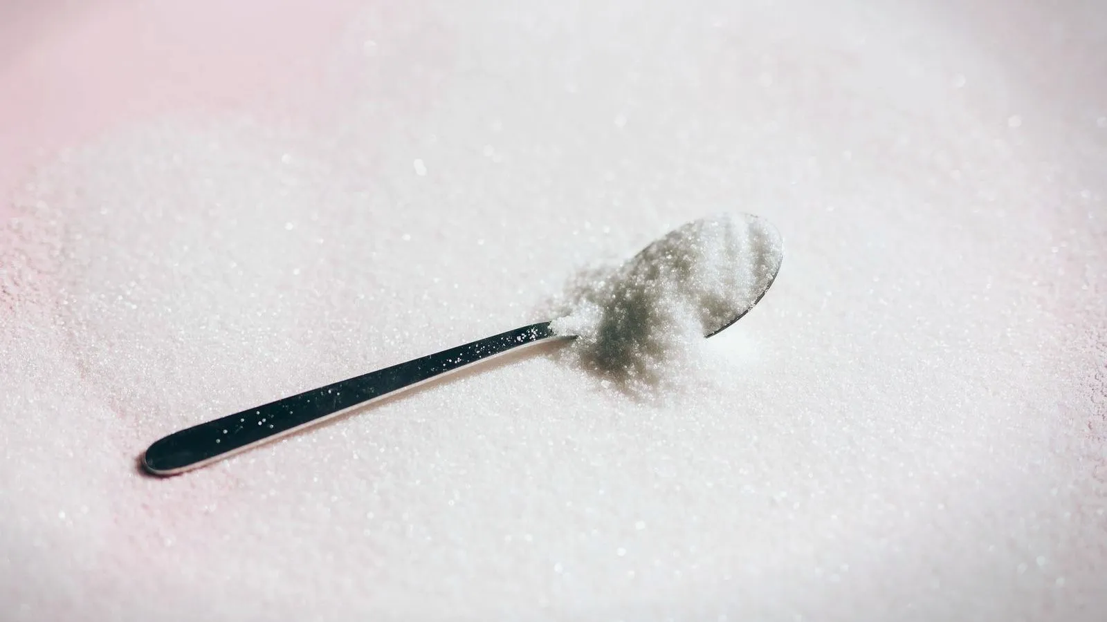 A teaspoon resting in a spread of white sweetener crystals