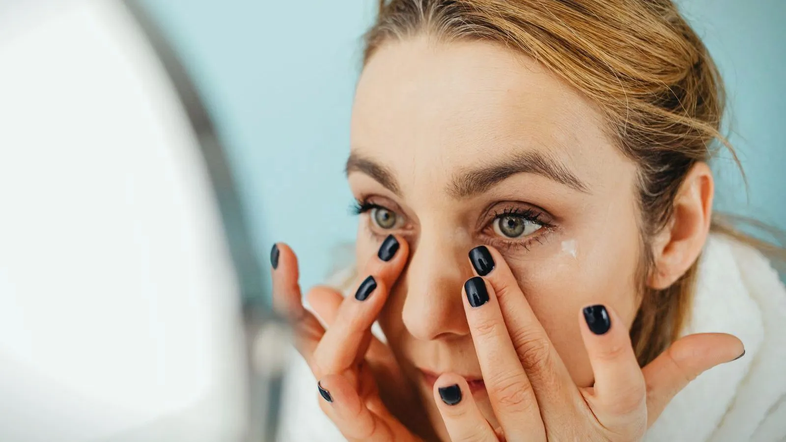A woman holding her eyelids open to put in eye drops