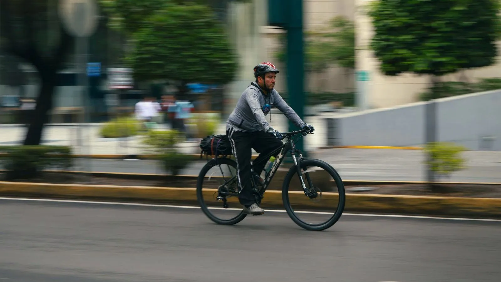 A cyclist riding along a city street with the background blurred by motion