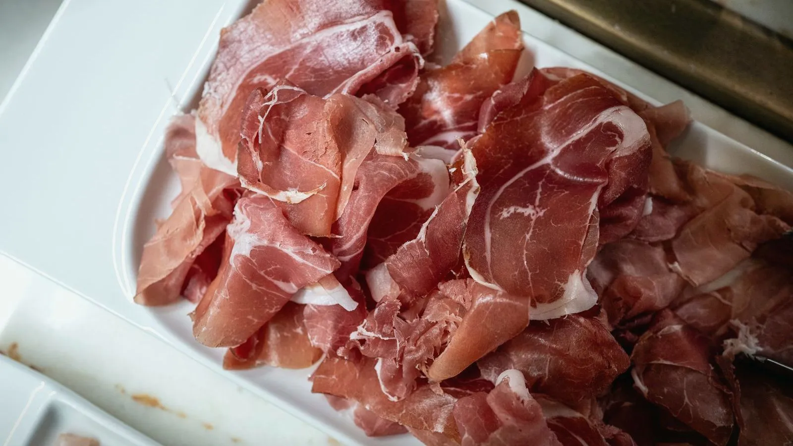 A tray of thinly sliced cured ham at a deli counter