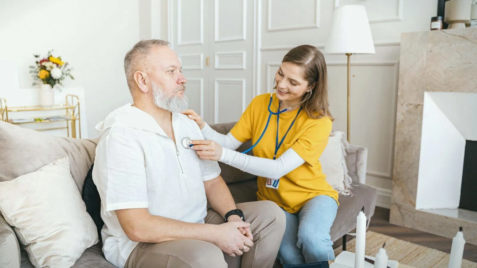A clinician listening to an older man's chest with a stethoscope