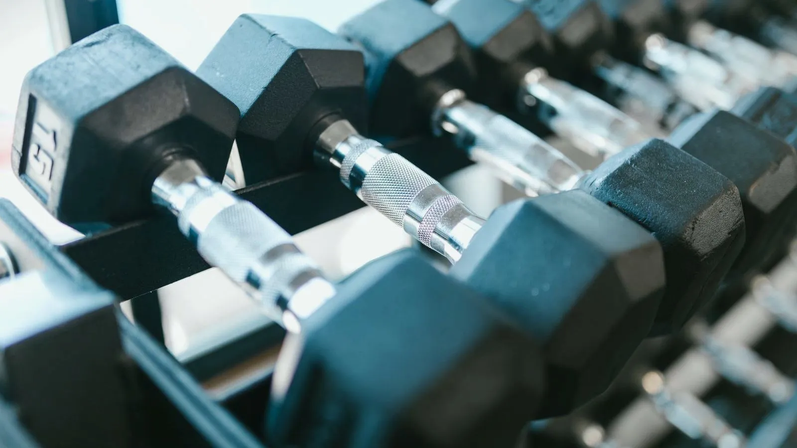 A rack of hexagonal dumbbells arranged by weight in a gym
