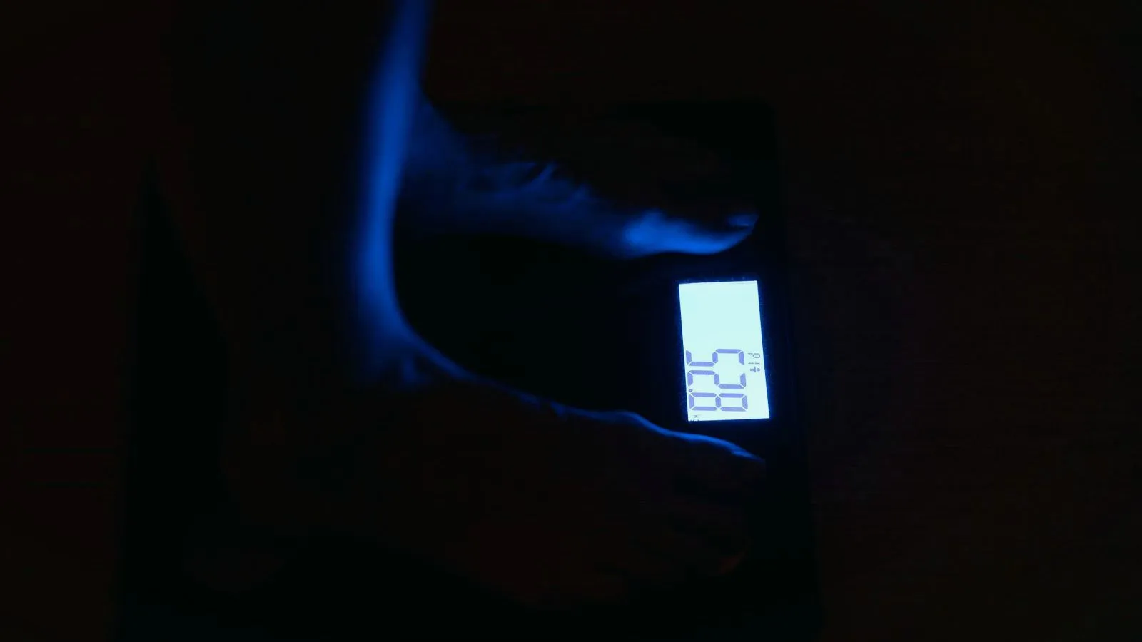 The lit display of a digital bathroom scale glowing in a dark room