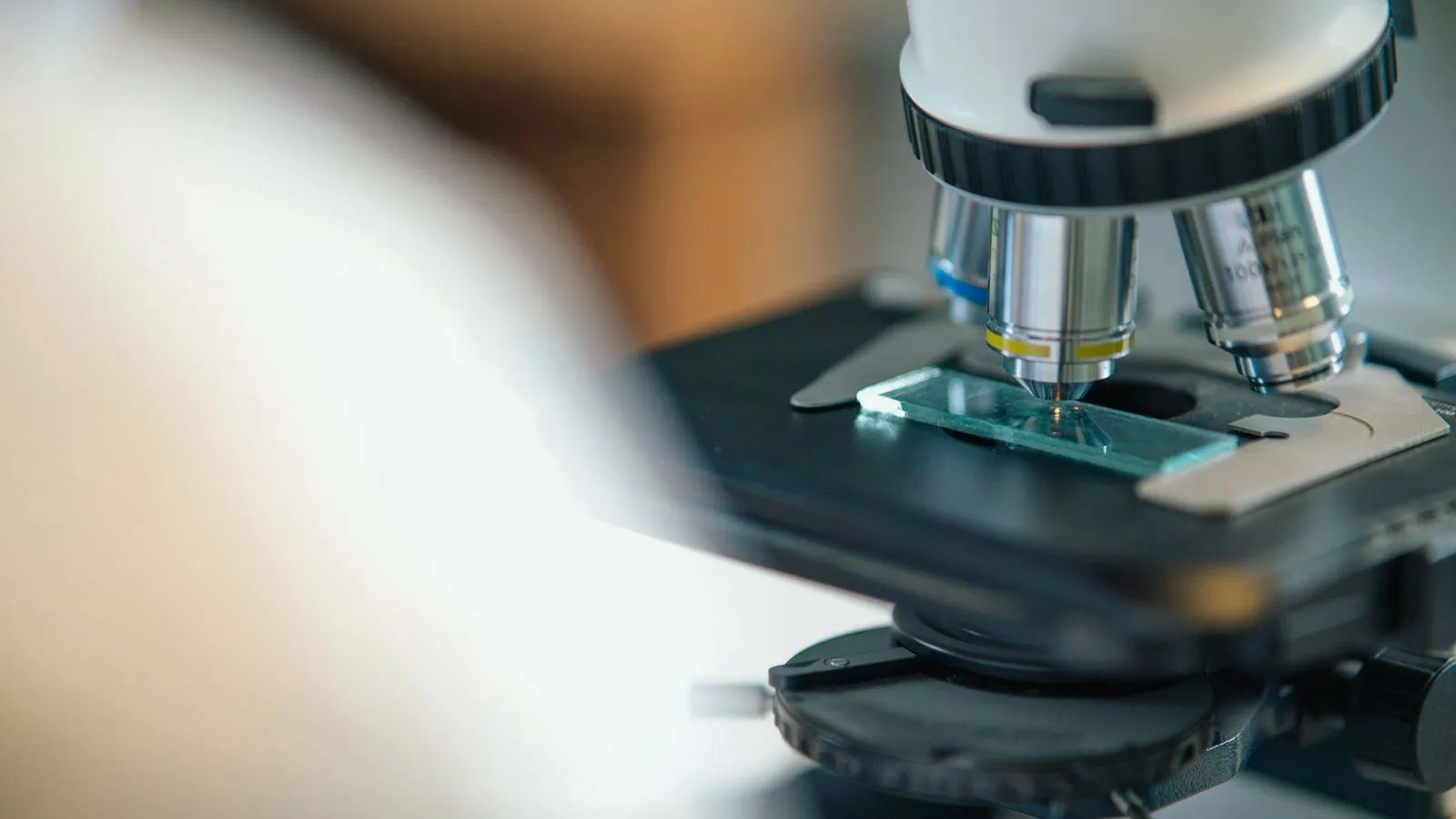 A microscope lens positioned over a glass slide on the stage.