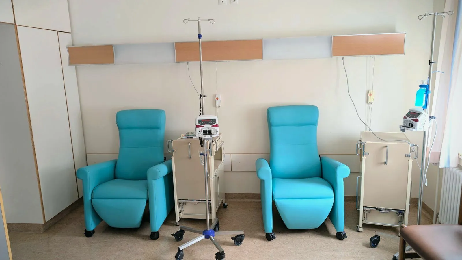 Two empty infusion chairs beside drip stands in a clinic room