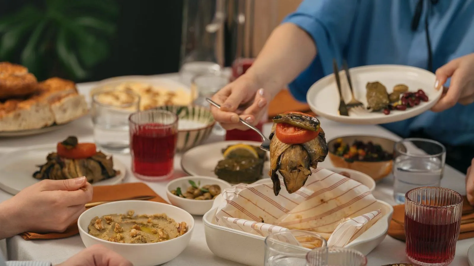 A shared table spread with small dishes as several people serve themselves