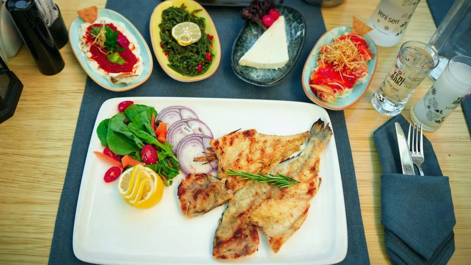 A table laid with grilled fish, salad and small mezze dishes