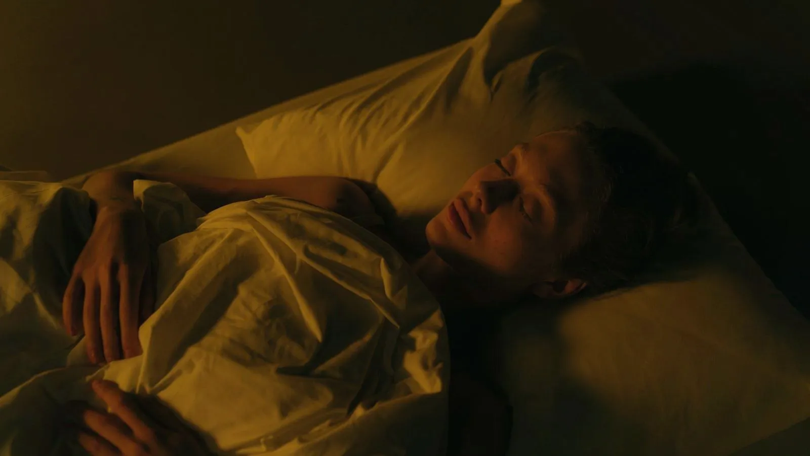 A person asleep in bed under warm low light