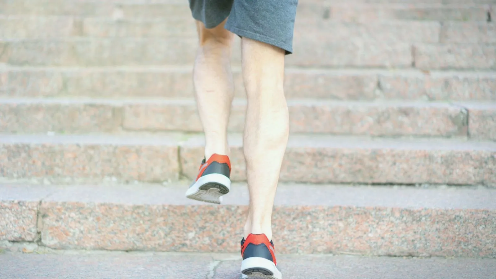A person's legs in running shoes climbing a flight of stone steps