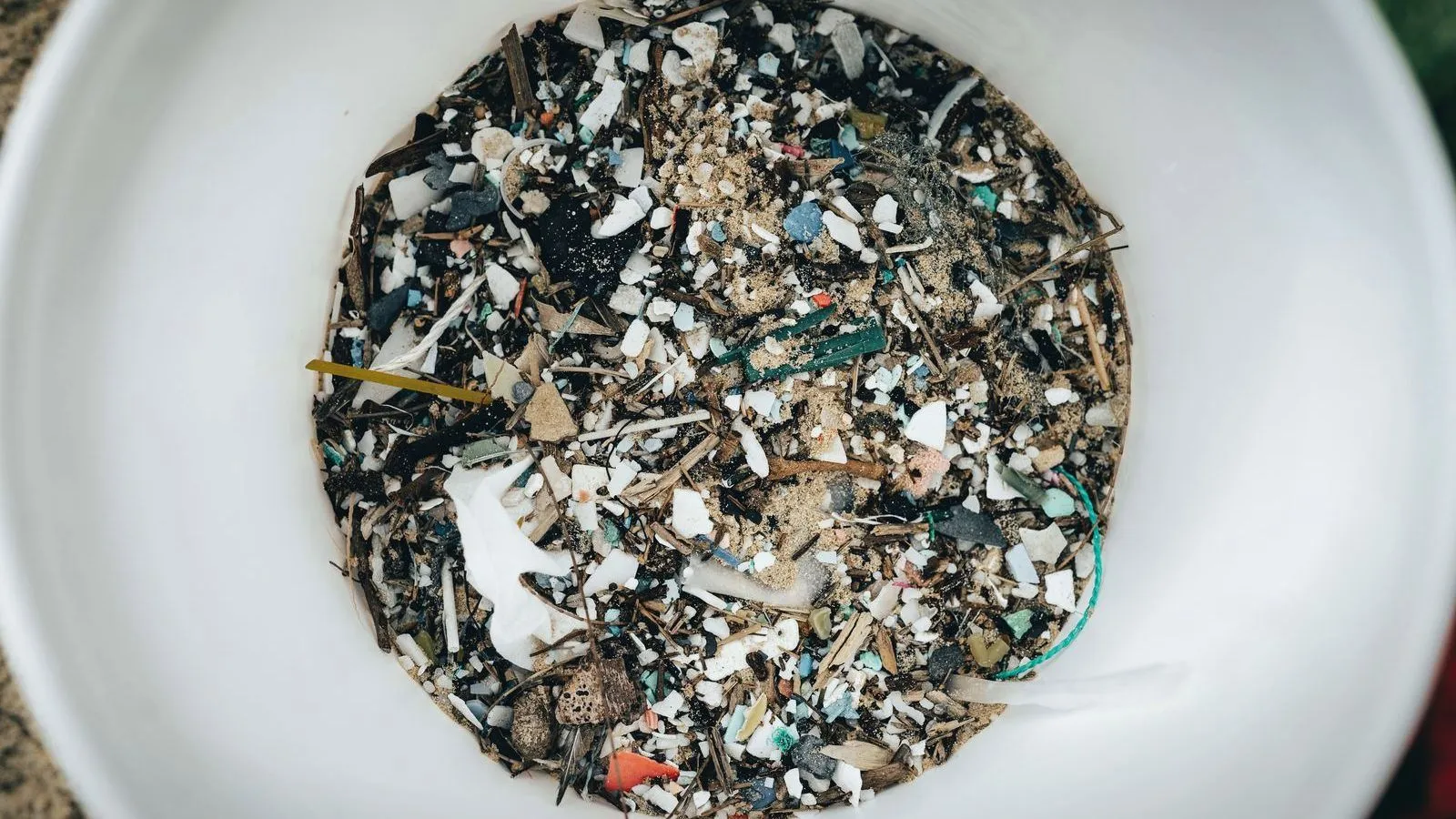 A white bowl filled with small, multicolored plastic fragments.