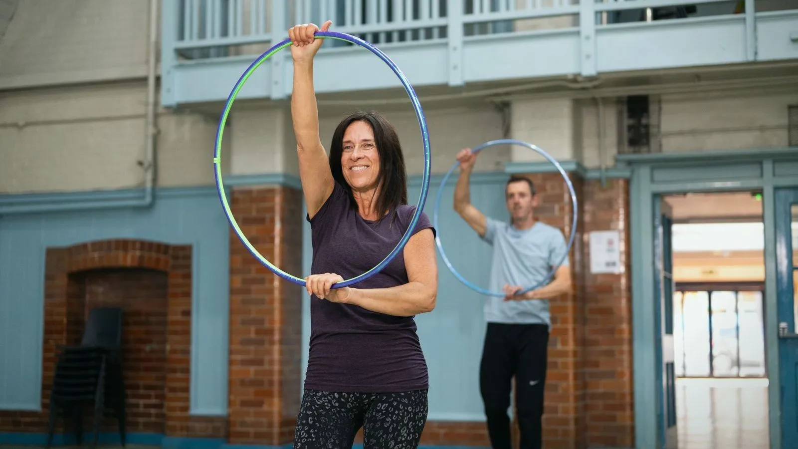 Adults holding weighted hoops in an exercise class in a brick hall