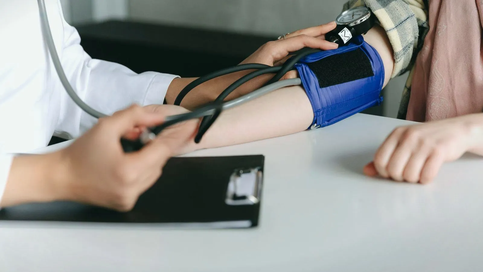 A clinician taking a patient's blood pressure with an arm cuff and stethoscope