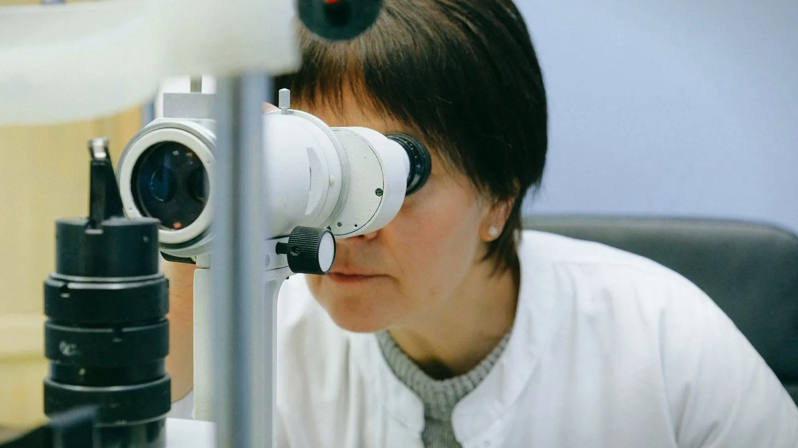 A clinician looking through the eyepiece of an eye examination microscope