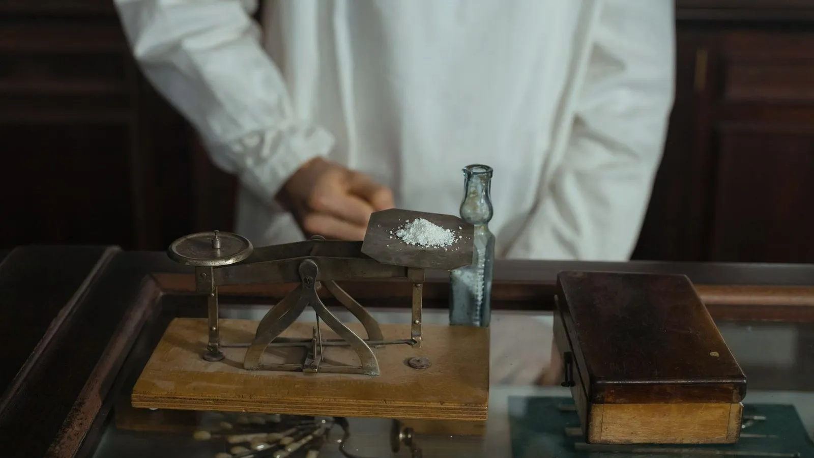 White powder being weighed on an antique brass apothecary balance