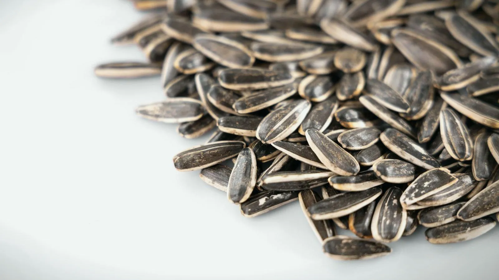 A pile of striped sunflower seeds on a white surface.
