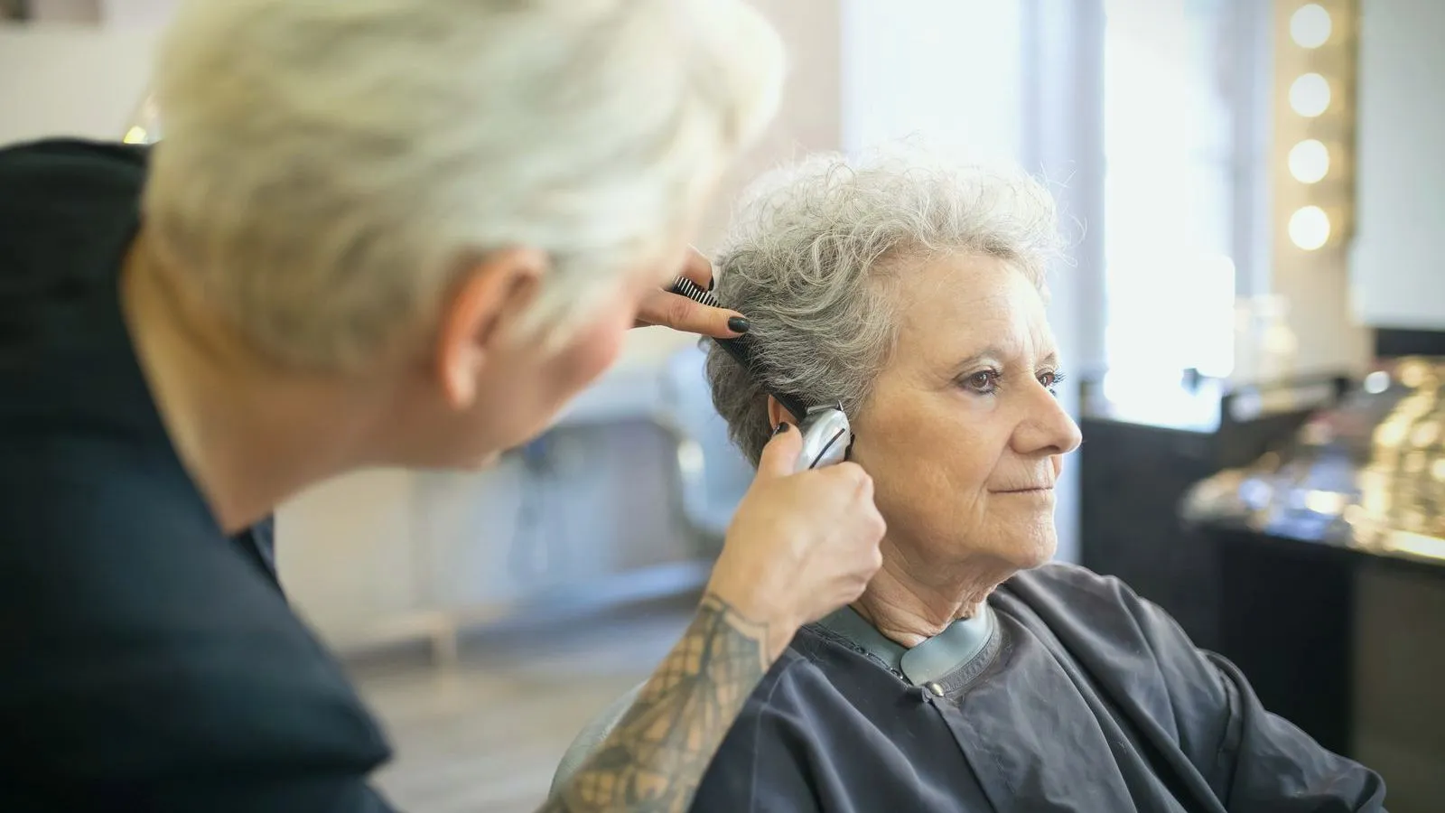 A clinician fitting a hearing aid behind an older woman's ear