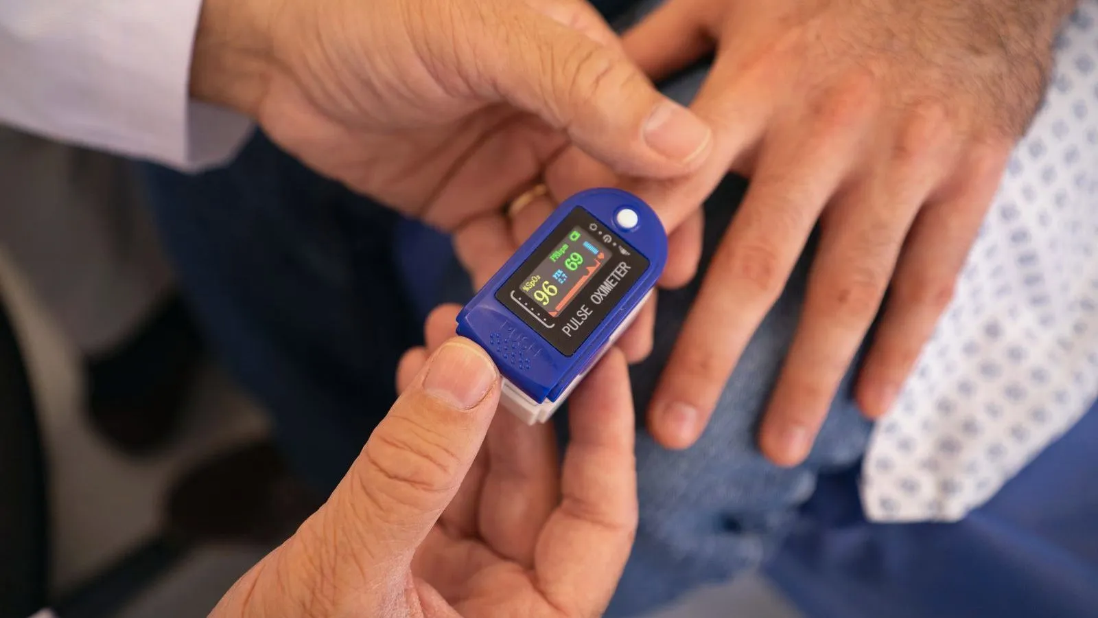 A pulse oximeter clipped onto a fingertip showing a reading