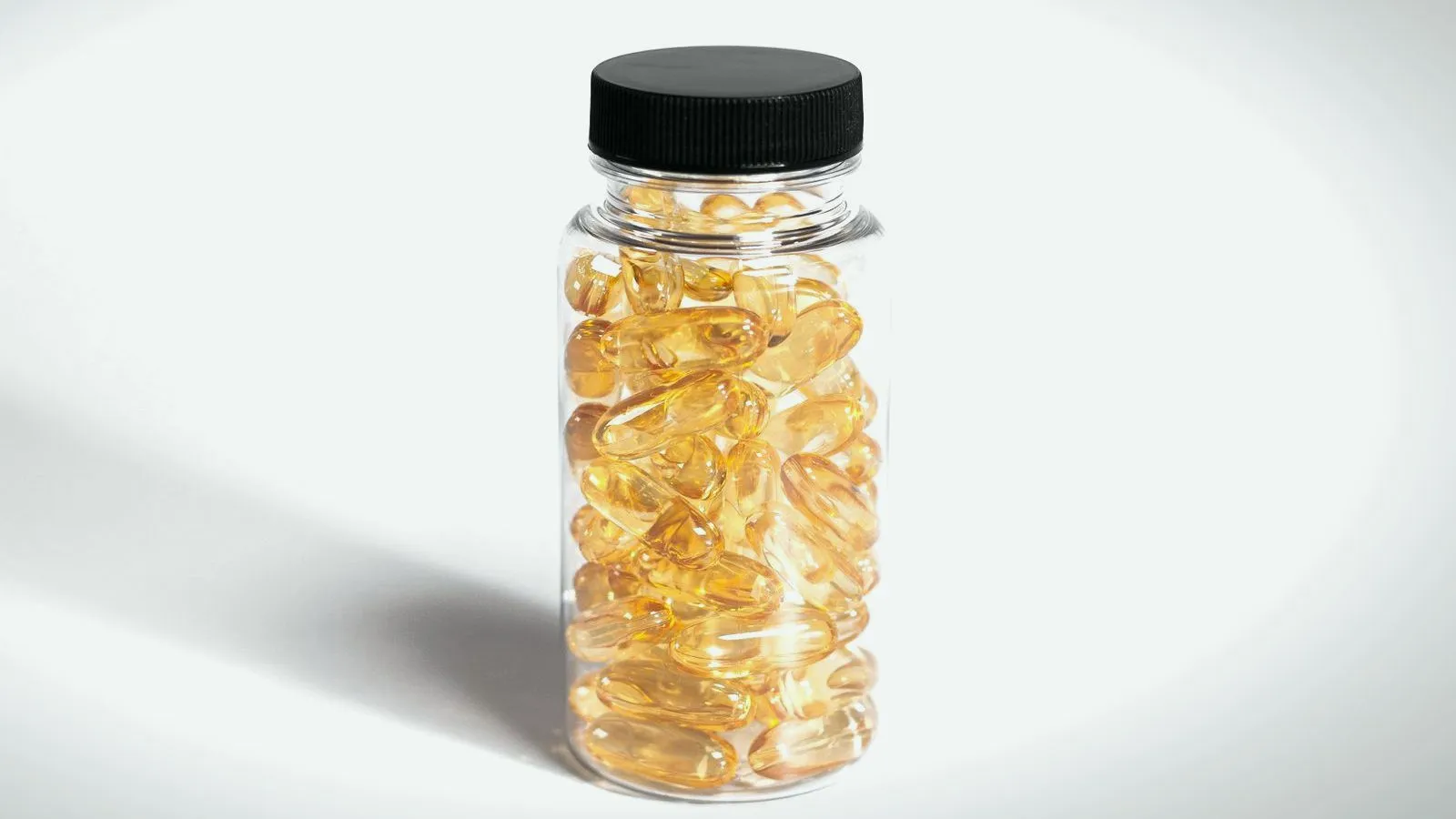 A clear, unlabeled bottle filled with golden softgel capsules.
