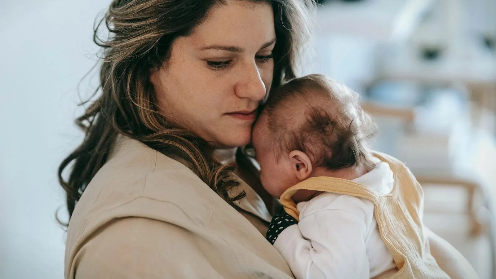 A mother holding her sleeping newborn against her cheek