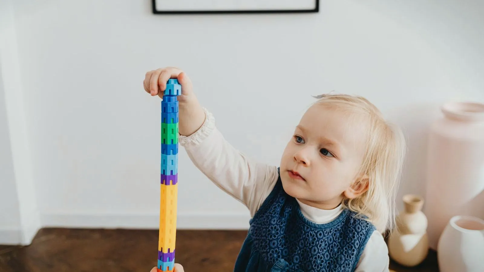 A toddler stacking colorful toy blocks into a tall tower.