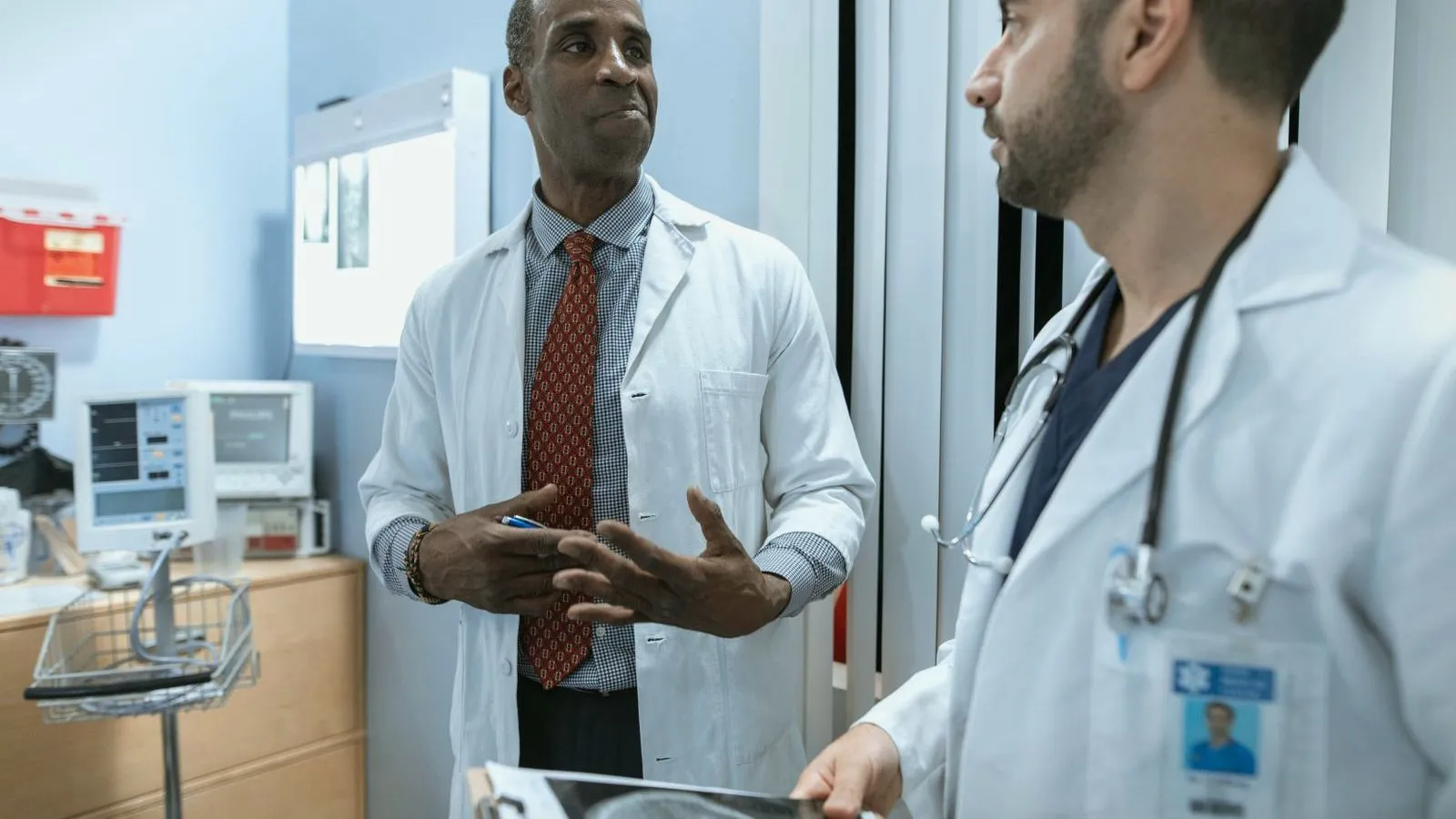 Two doctors in white coats talking in a clinical room