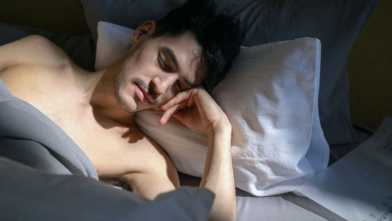 A man asleep on his side in bed in soft morning light
