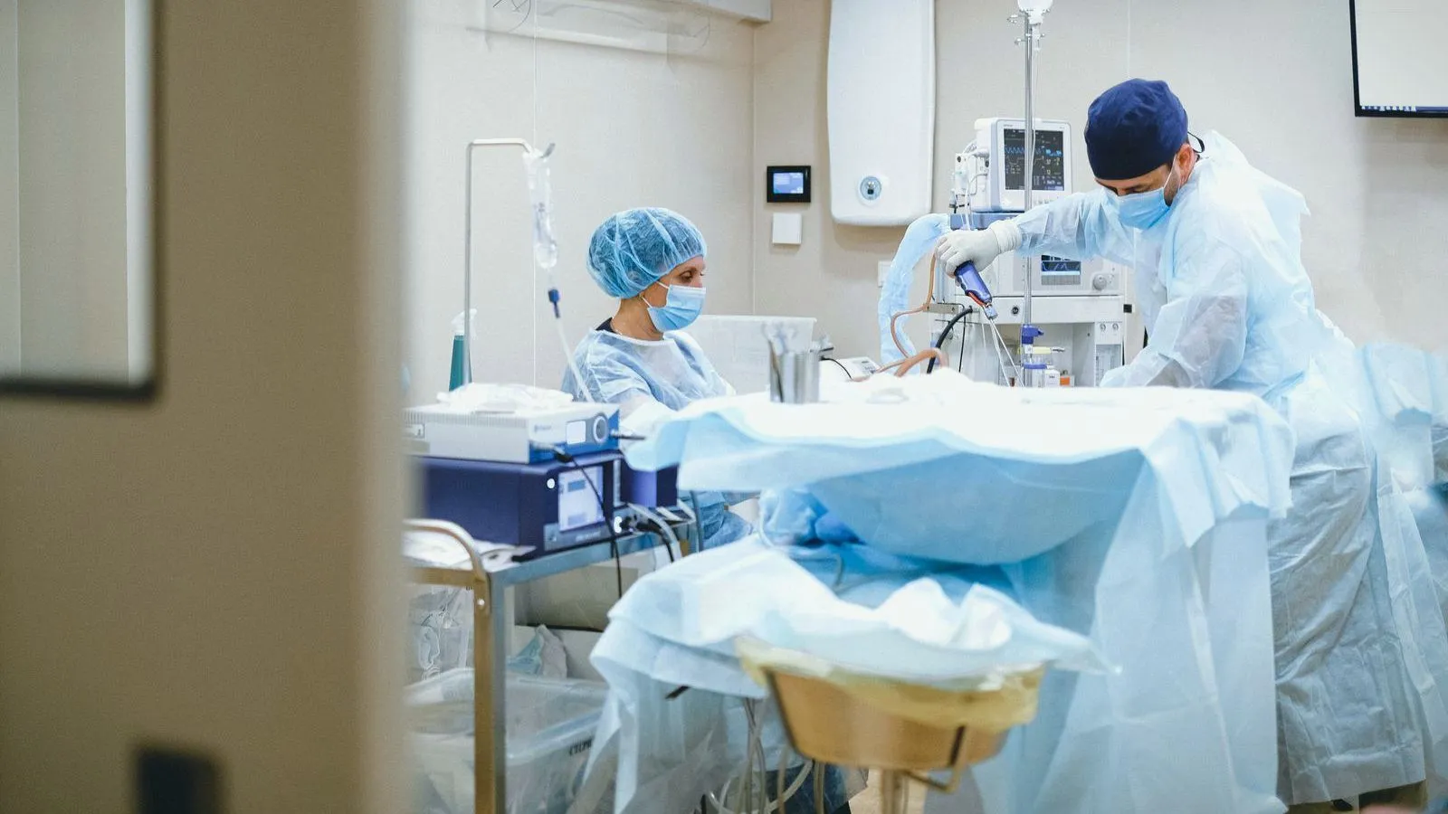 Two gowned surgeons working over a fully draped patient in an operating room