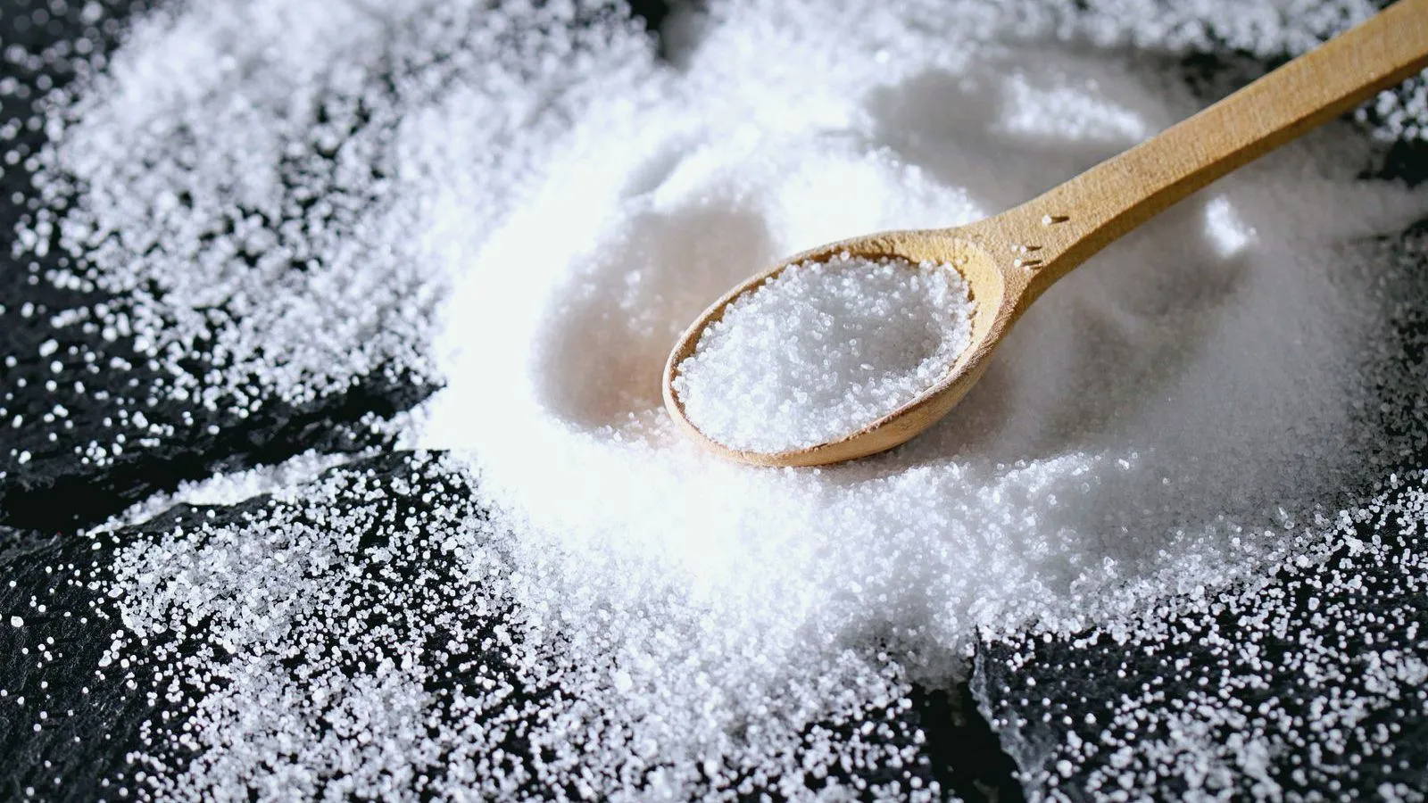 A wooden spoon resting in a heap of coarse white salt