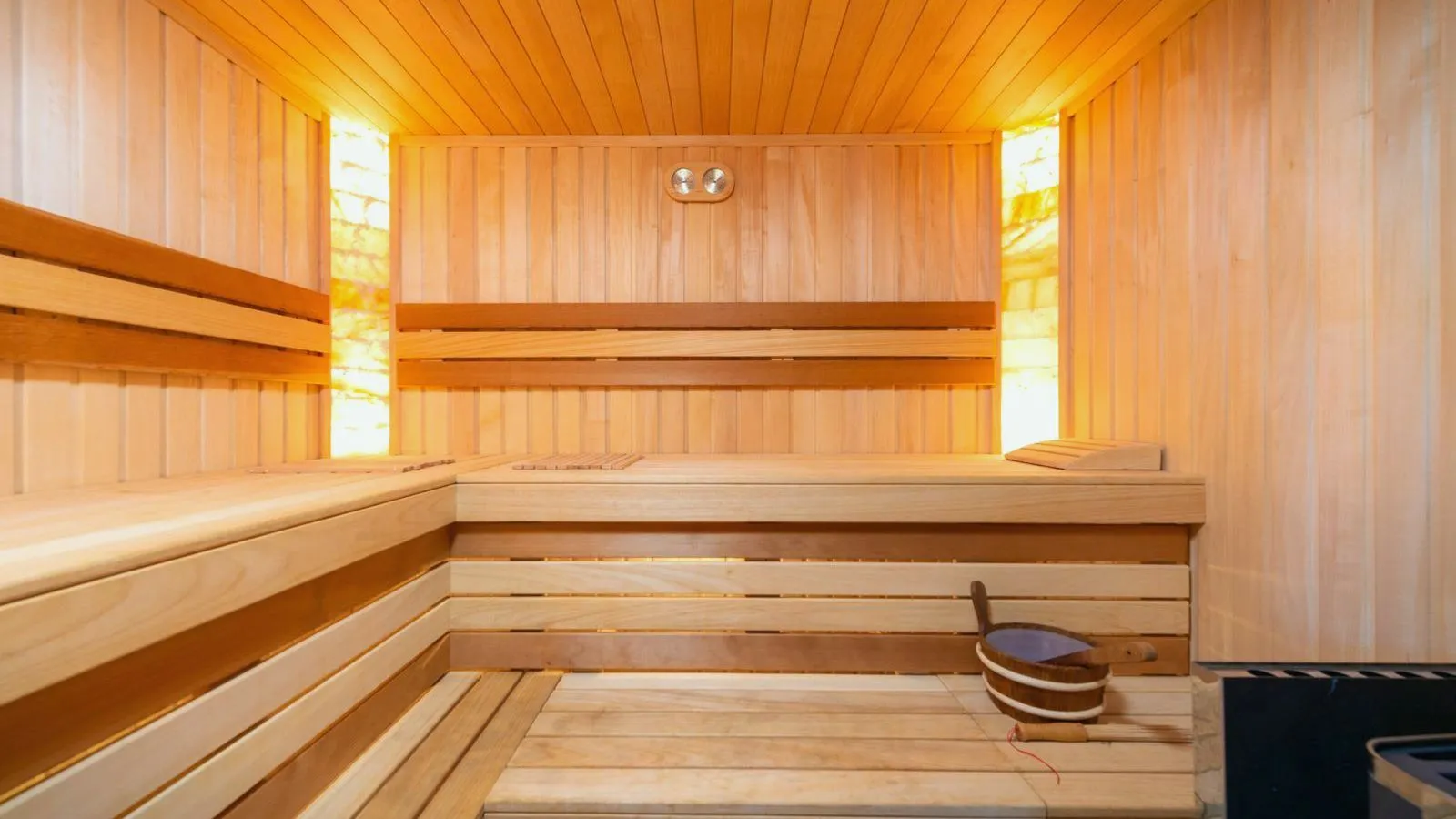 The empty wooden benches of a sauna lit by warm lights.