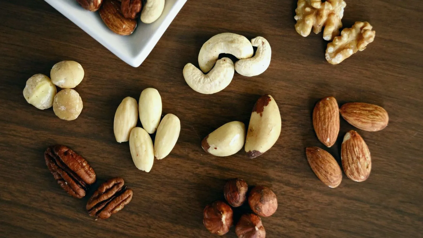 Mixed nuts including brazil nuts scattered on dark wood