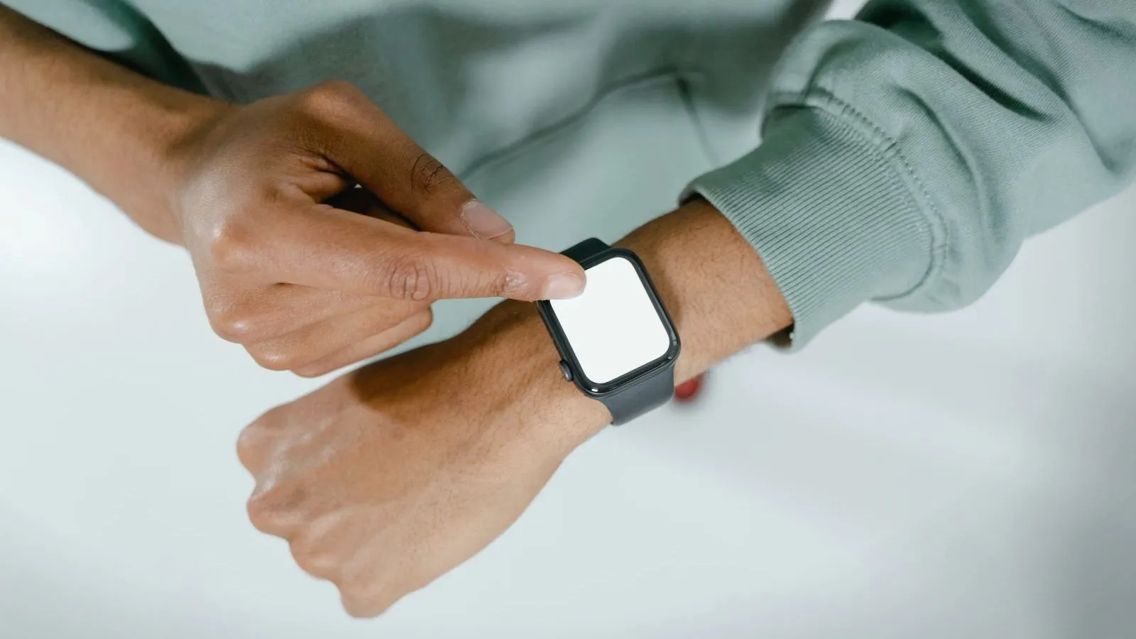 A person tapping a smartwatch with a blank screen worn on the wrist.