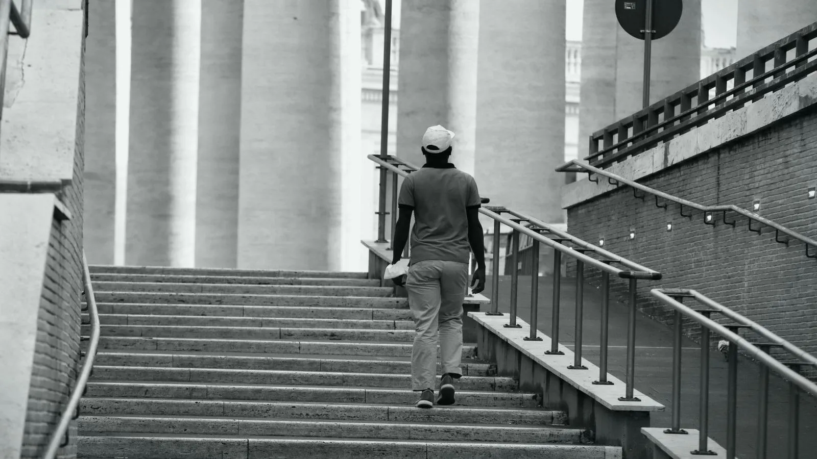 A man walking up a wide flight of public stone steps, seen from behind