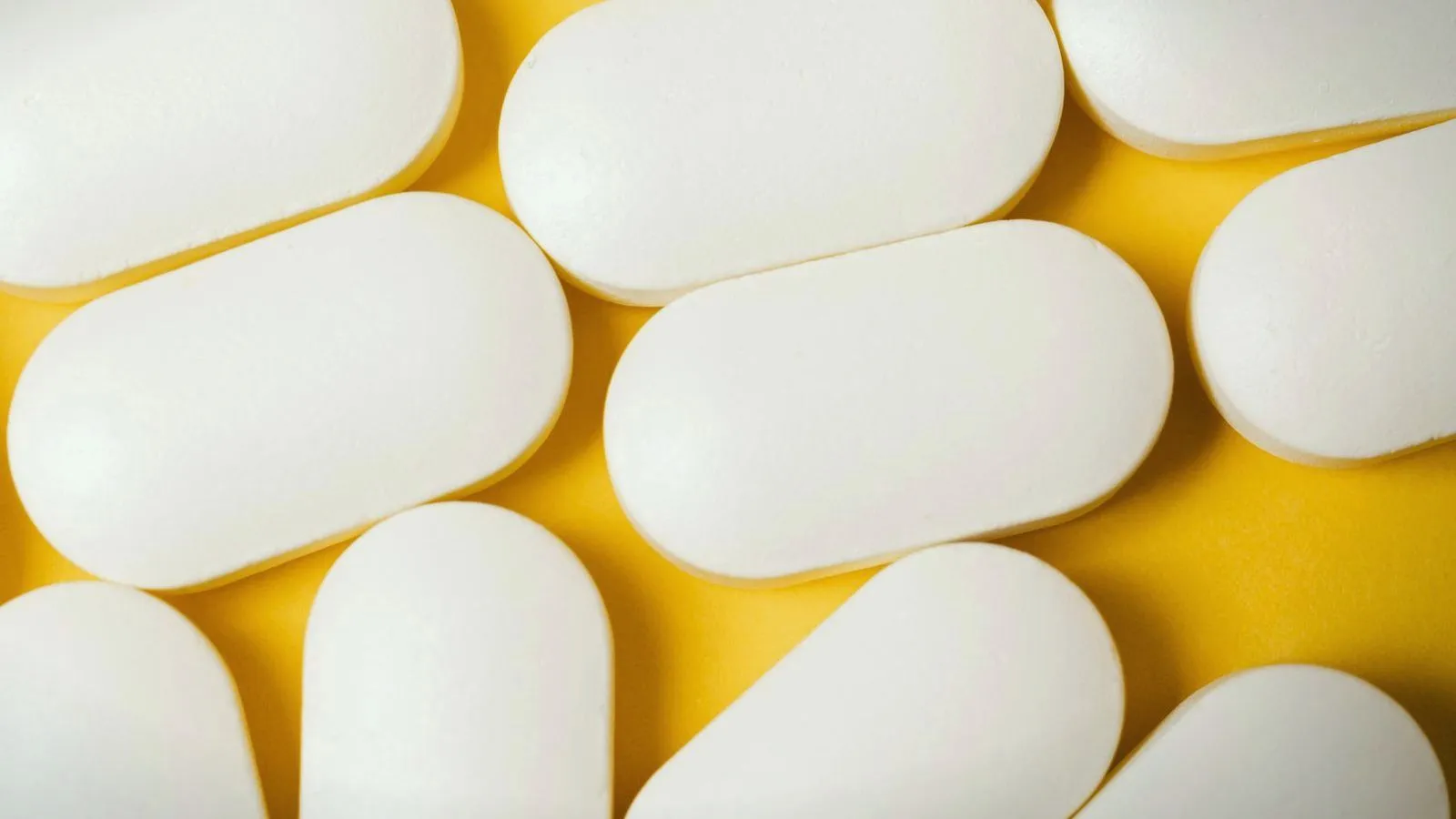Large white oblong tablets filling the frame on a yellow background