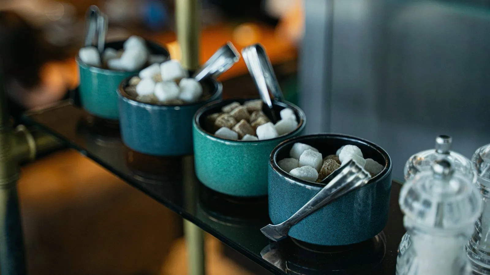 Bowls of white and brown sugar cubes with serving tongs
