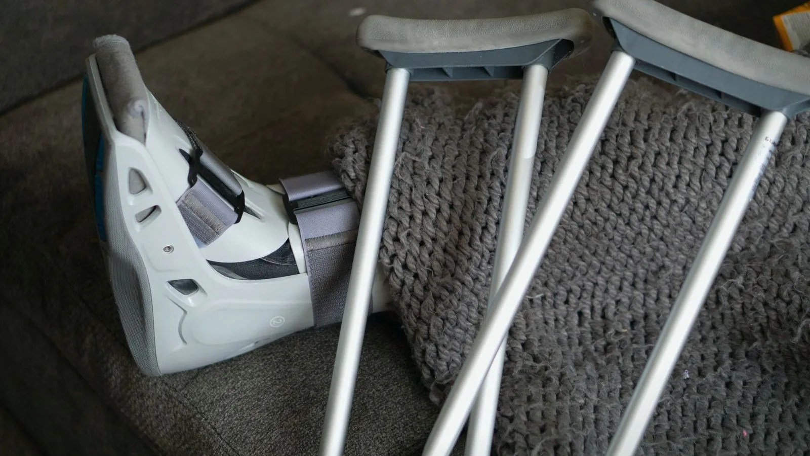 A moulded walking boot resting beside a pair of crutches