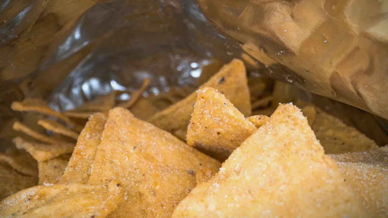 Tortilla chips in an open snack bag, close up.