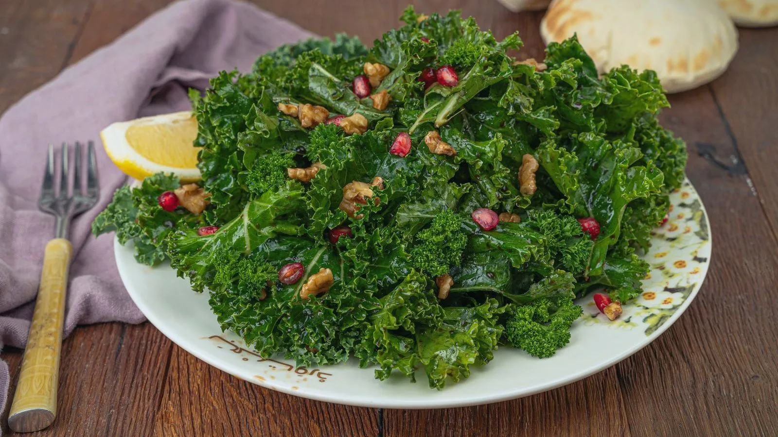 A kale salad topped with walnuts and pomegranate seeds