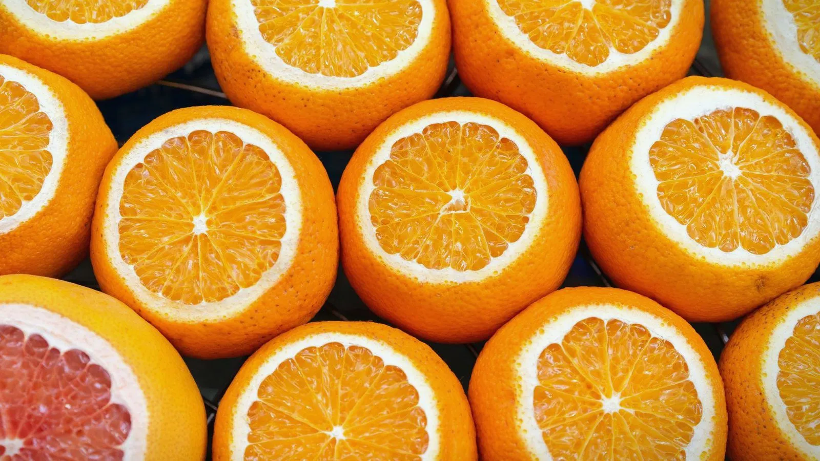 Halved oranges and a grapefruit packed together, cut sides up