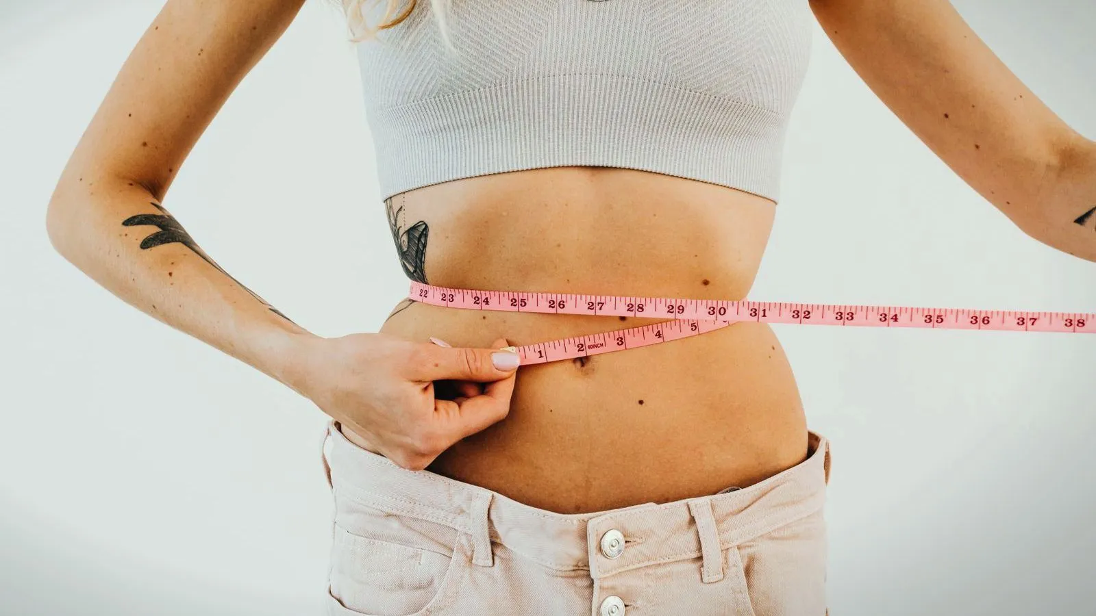 A person measuring their waist with a tape measure.