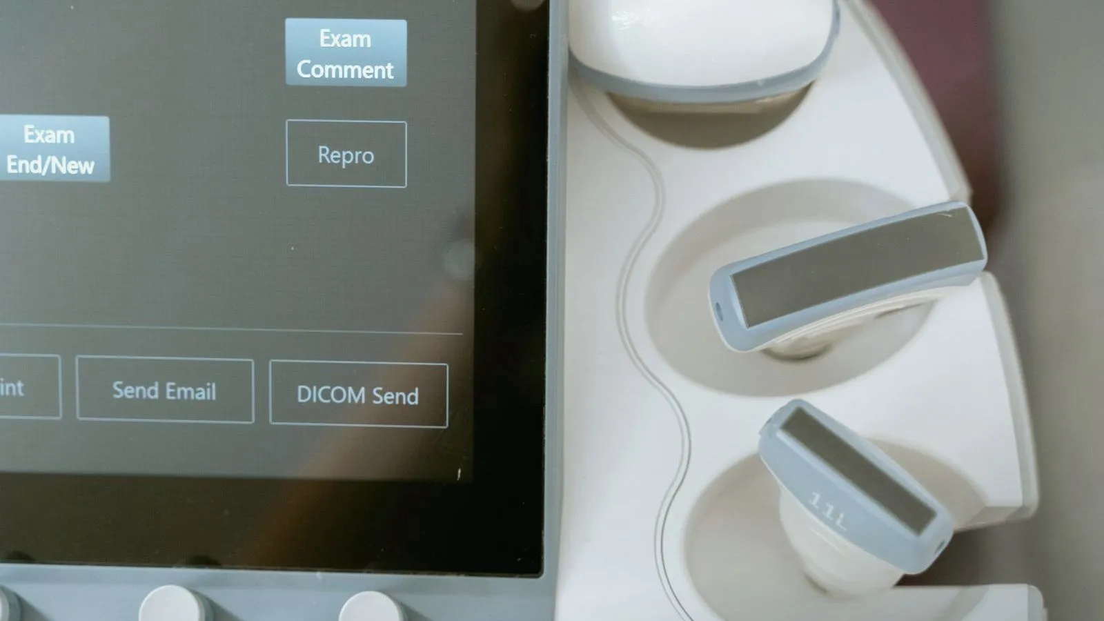 An ultrasound console screen beside two probes in their holders